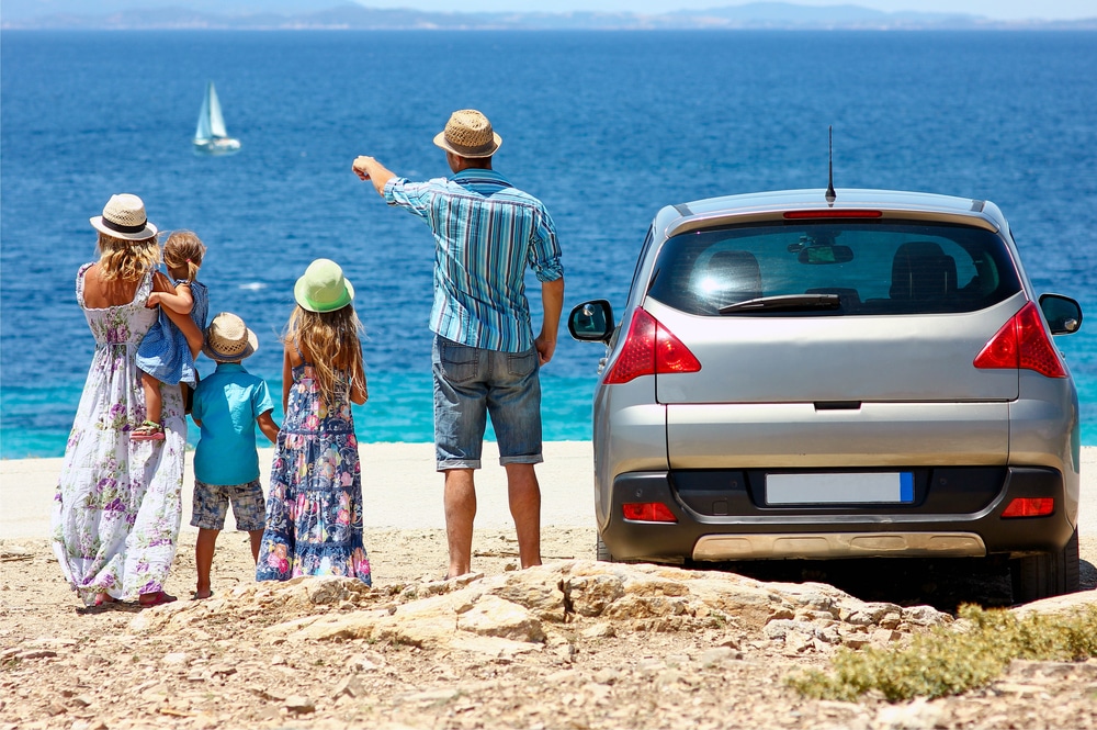 famiglia con bambini piccoli vicino all'auto al mare